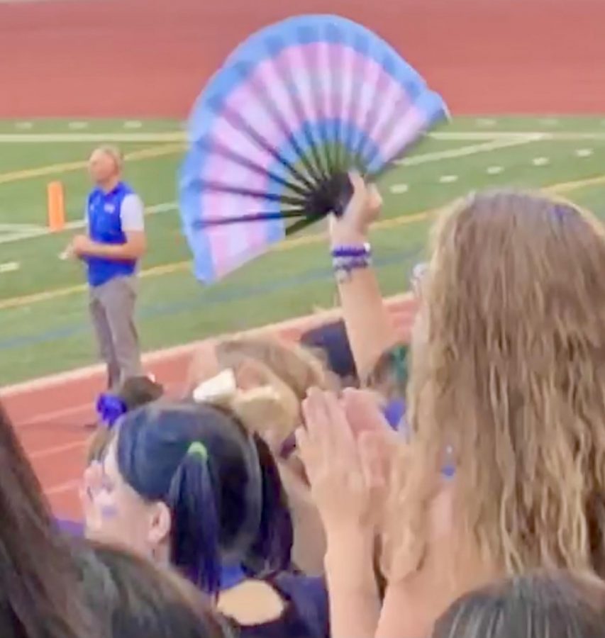 A student waves a fan sporting the trans pride flag in the student section of Powderpuff