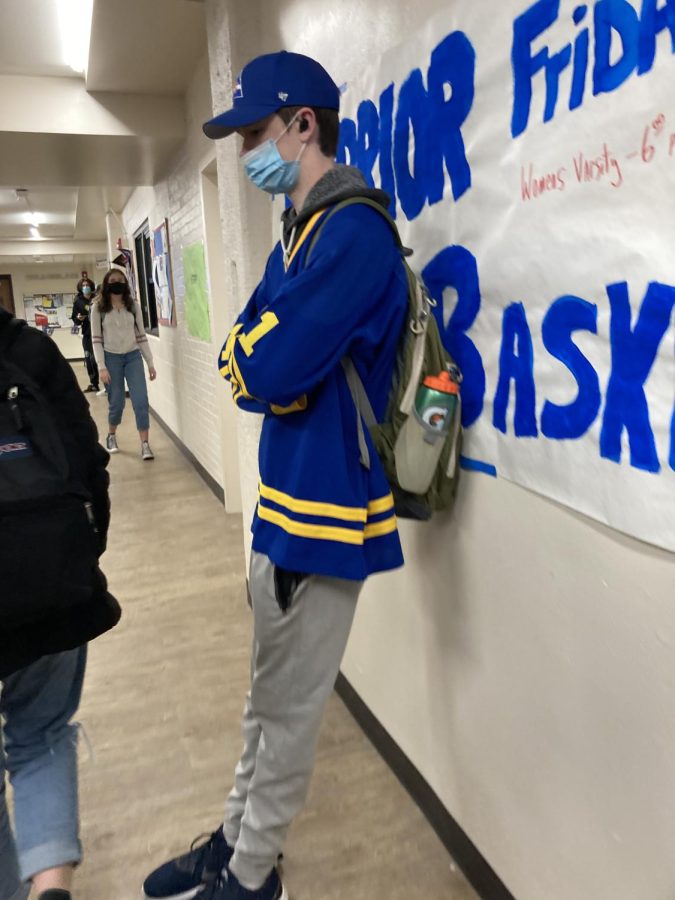 A student in blue against a poster advertising Friday night’s (Feb. 4th) basketball game.