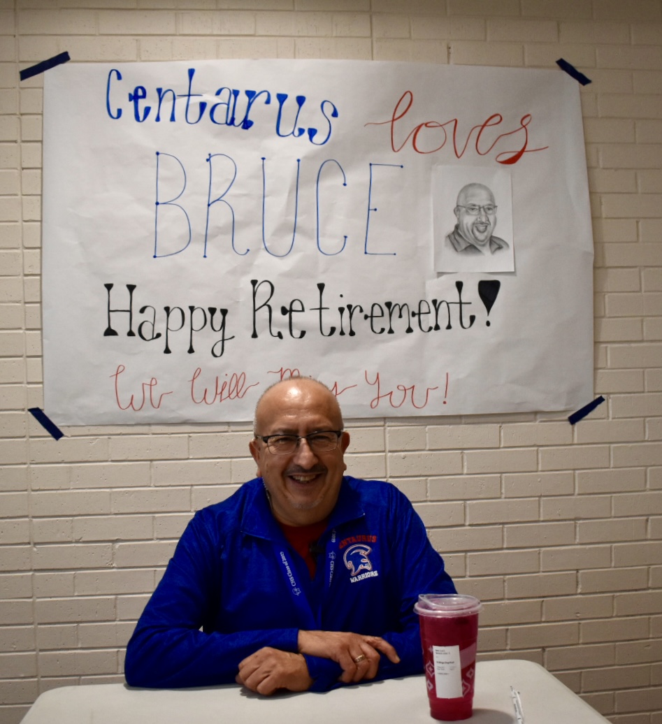 Bruce+sits+at+his+table+in+the+main+hallway%2C+waiting+to+greet+students+as+they+walk+in+for+first+period.