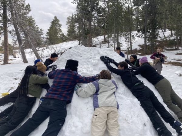2/2 - Students hug their snow shelter to solidifiy the walls before inserting sticks as width markers. They named the shelter Juanito Pepito Photo Courtesy of Ms. Llager, CLDE teacher. 